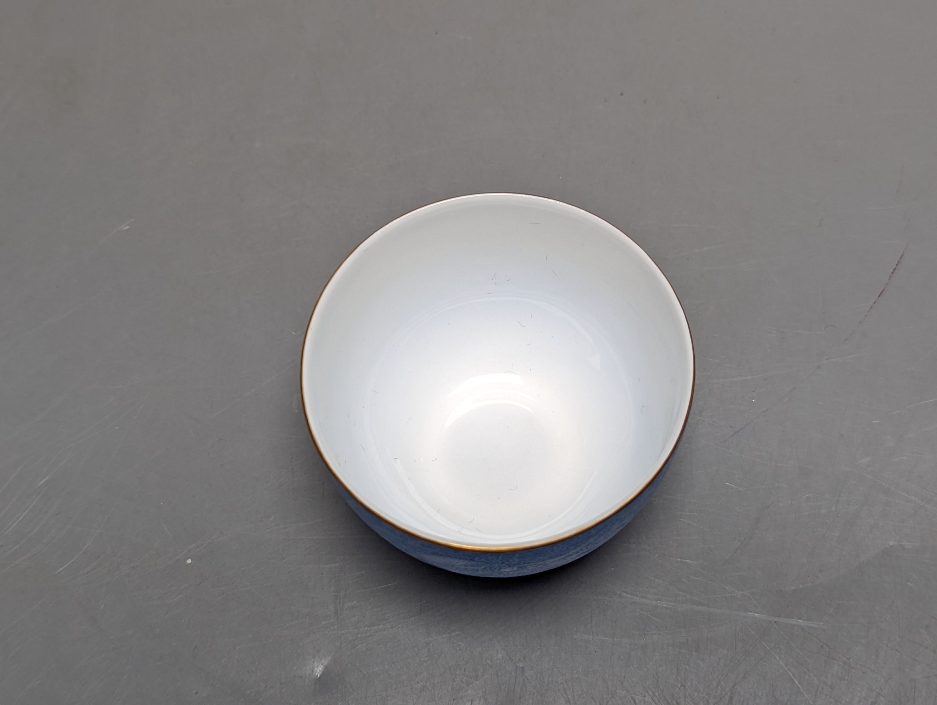 A Japanese or Chinese sgrafitto blue enamelled cup, cased. 6cm diameter
